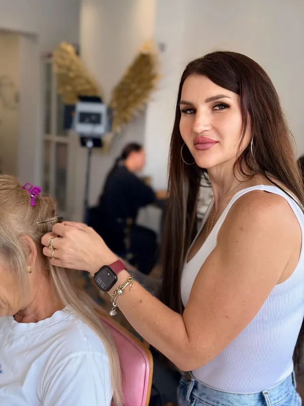 Specialist Maria Balan professionally fitting keratin hair extensions on a client in salon